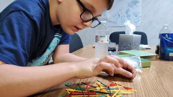 Autistic boy playing with pickup sticks