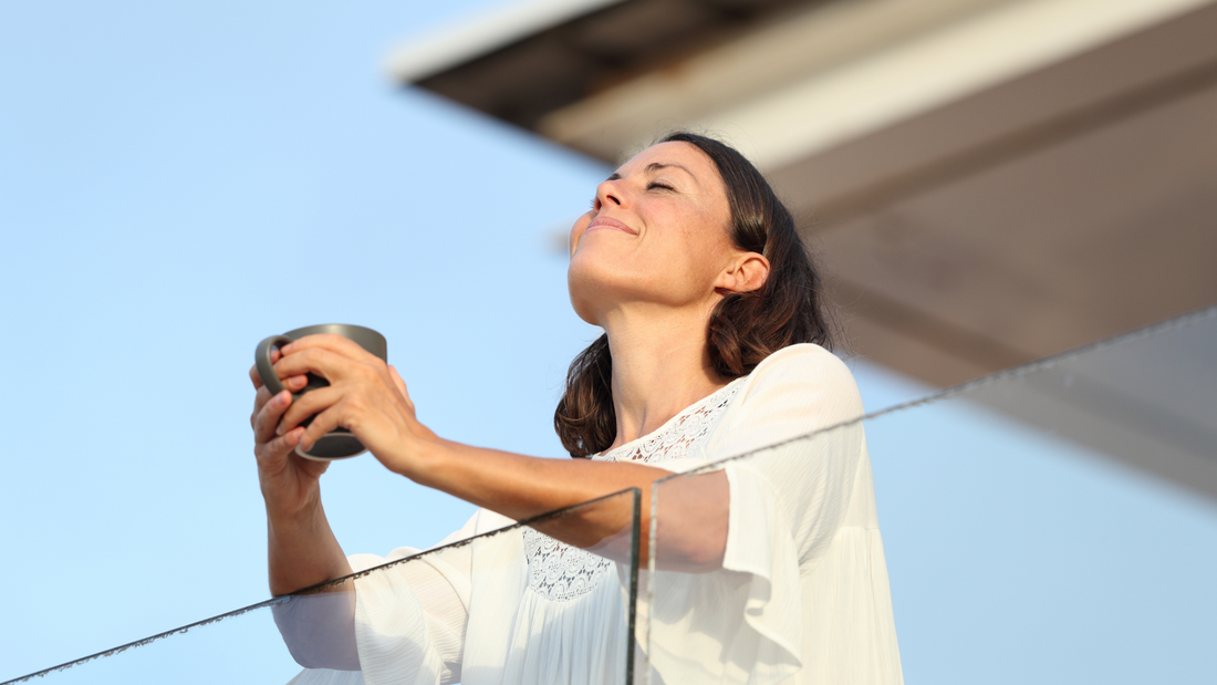Serene woman outdoors on a sunny day with a cup of tea. Probiotics for stress.