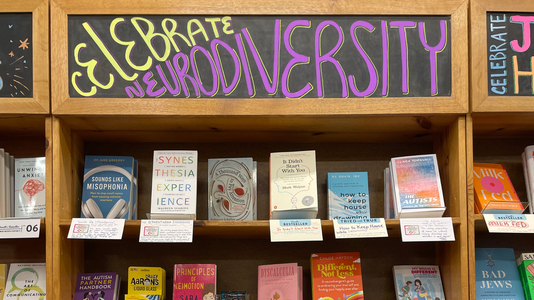 A chalk board above a bookshelf of bookstore books reads Celebrate Neurodiversity