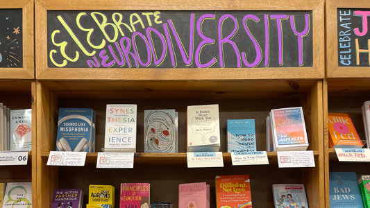 A chalk board above a bookshelf of bookstore books reads Celebrate Neurodiversity