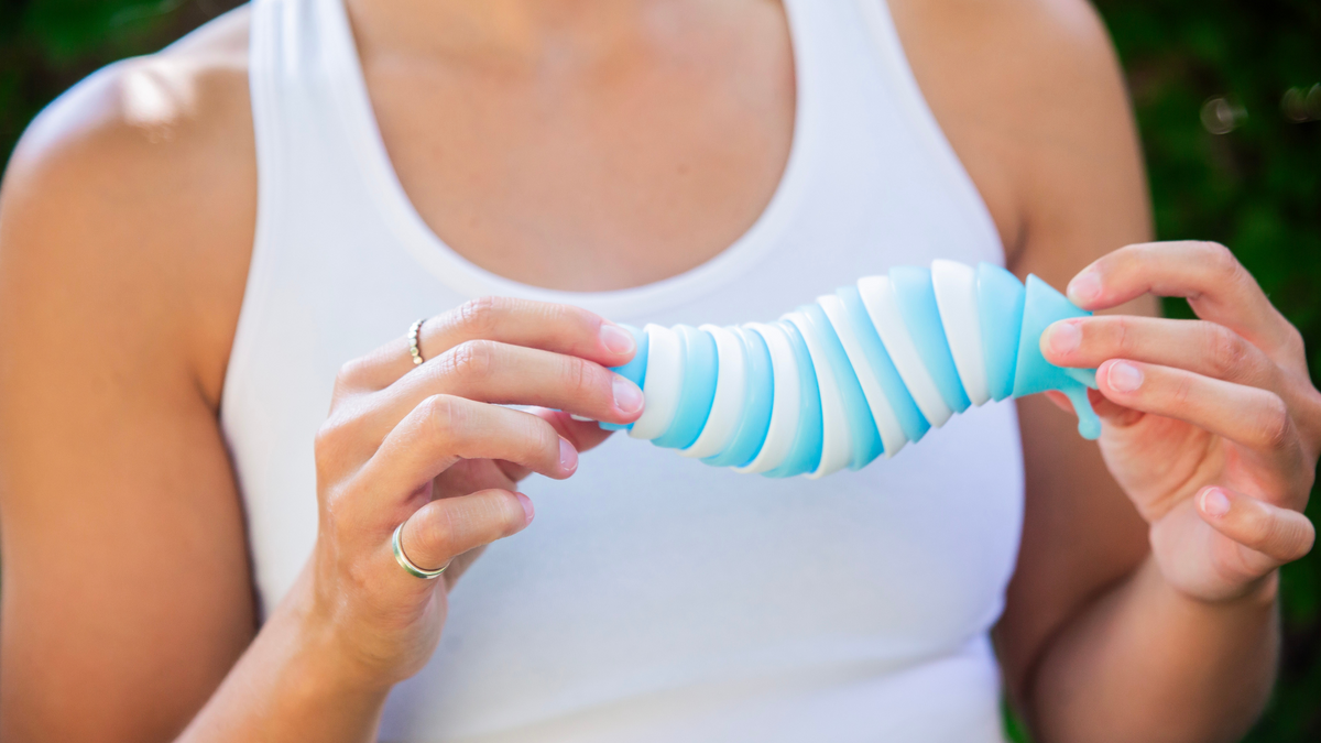 A woman in a white tank top holds a white and blue fidget toy