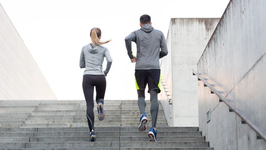 Man and woman running up a flight of stairs